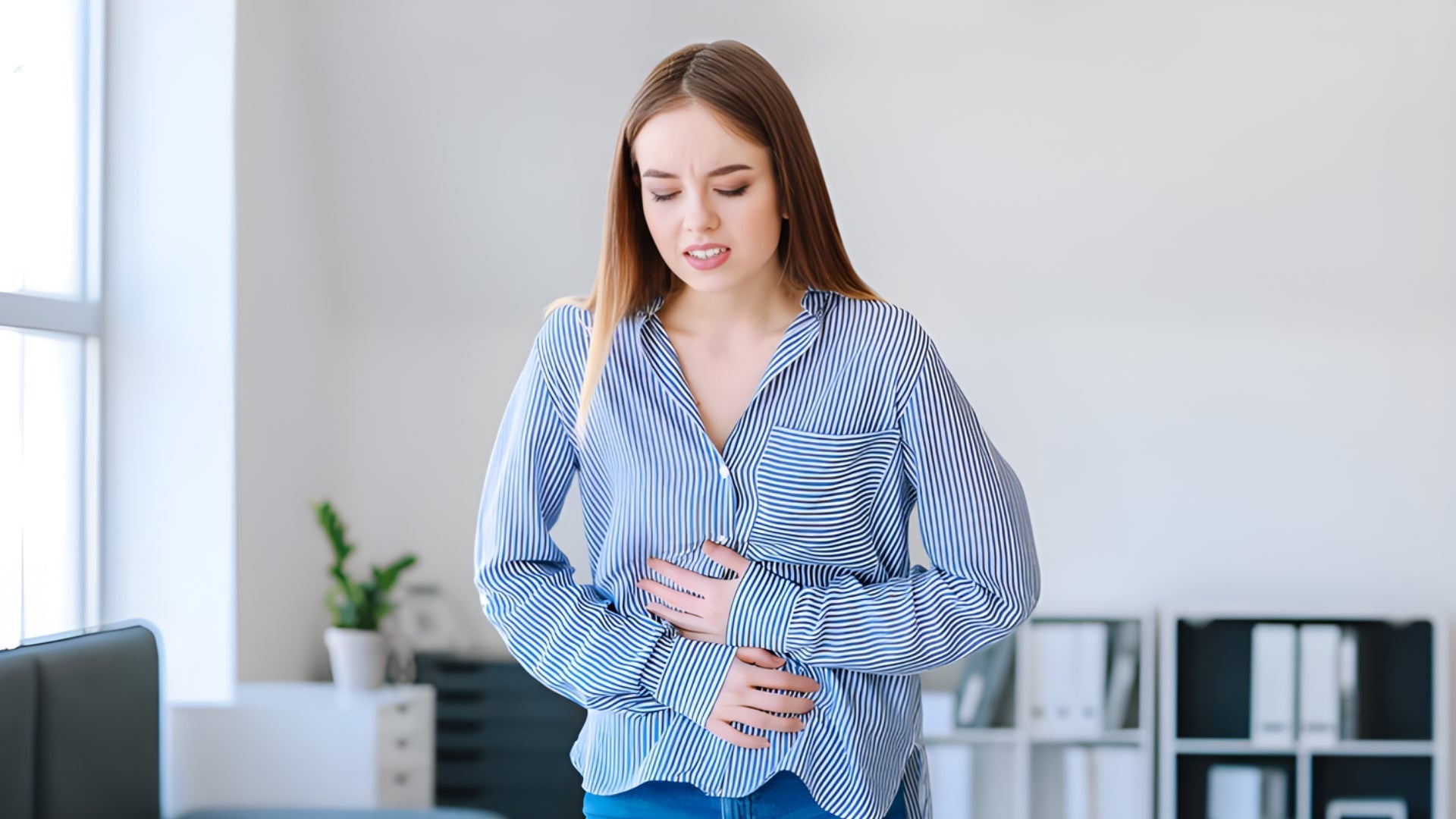Woman experiencing stomach pain in office