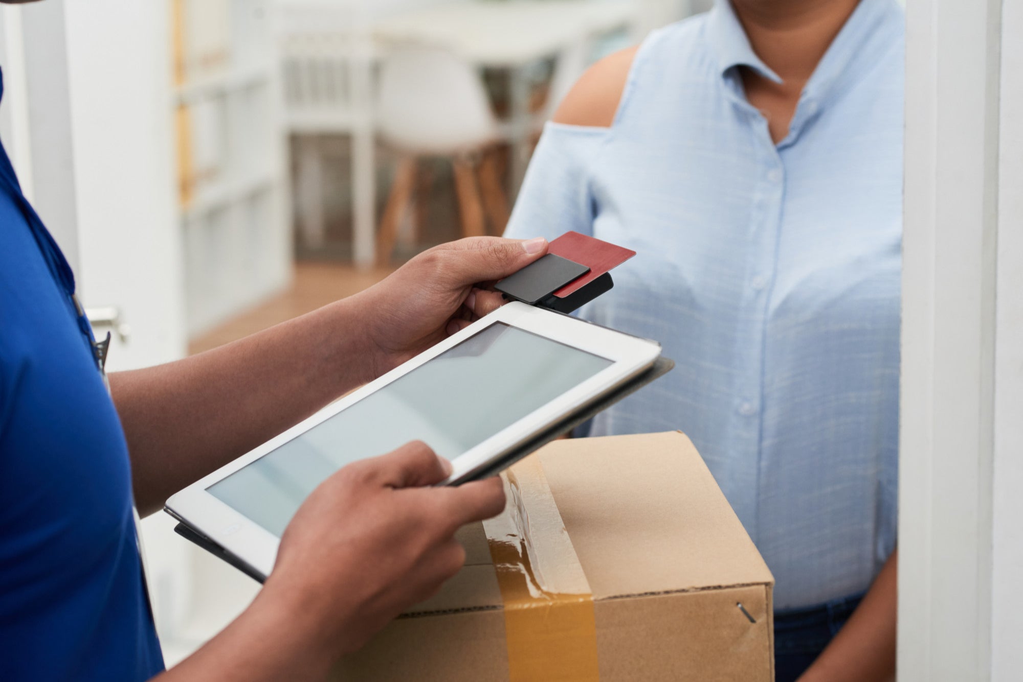 Person using a tablet to scan a package with another person holding a card.