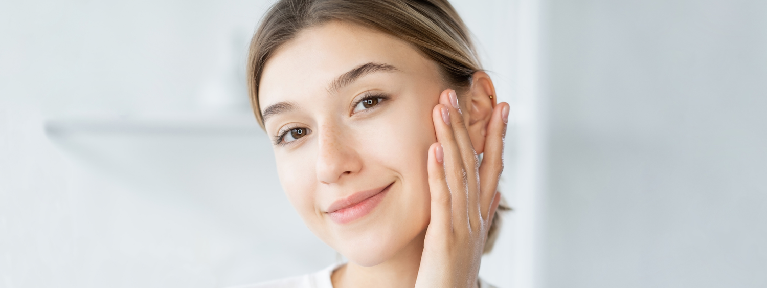Woman with clear skin smiling and touching her face gently.