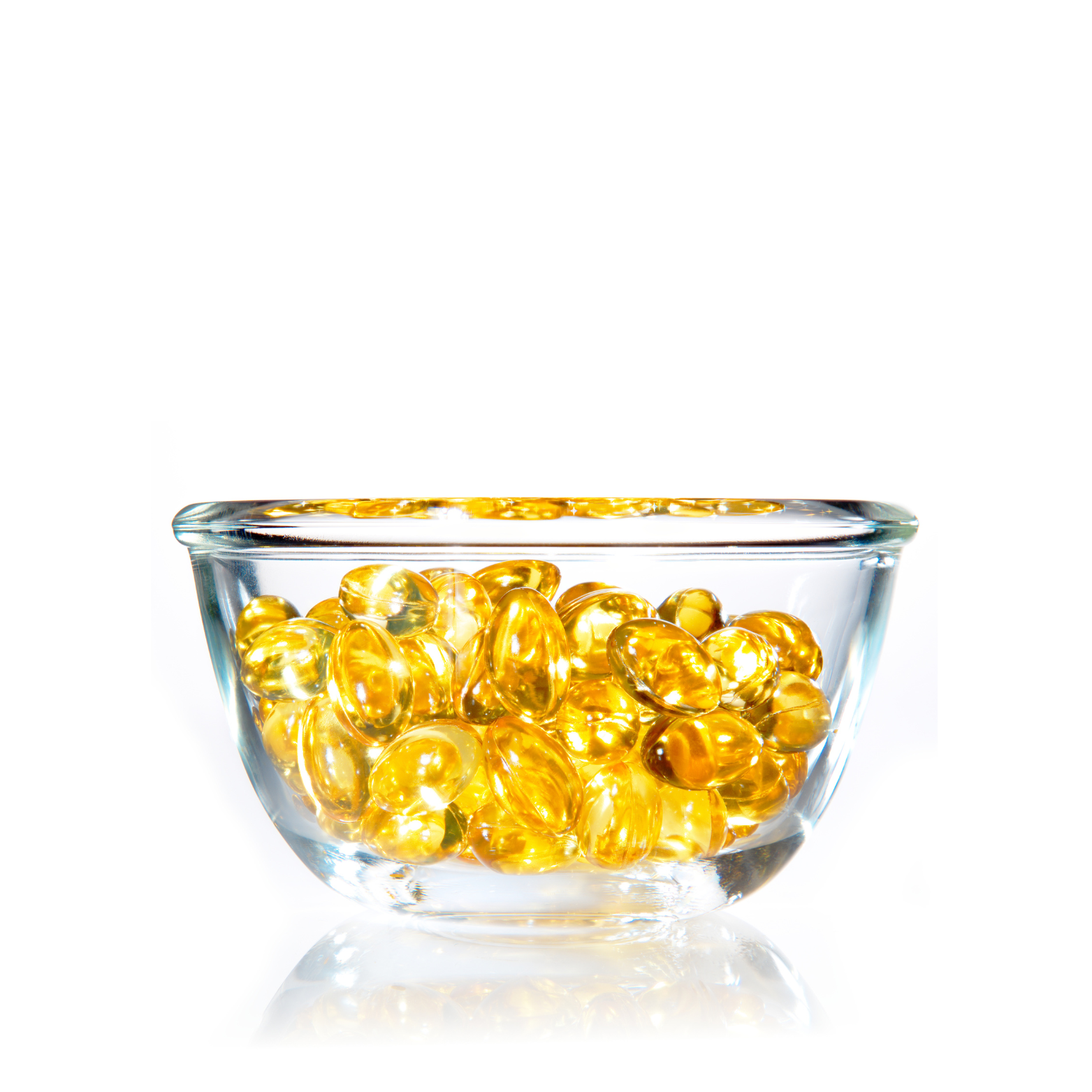 Clear glass bowl filled with golden softgel capsules on white background.