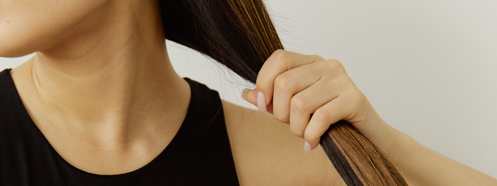 Woman holding long, healthy hair to show castor oil benefits.