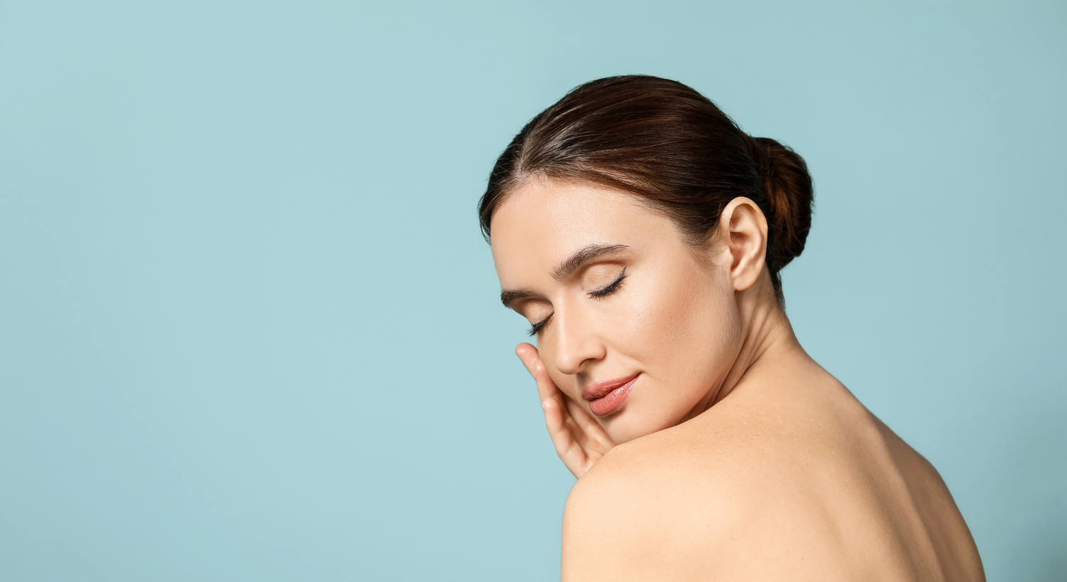 Woman embracing clean beauty with glowing skin on blue background.