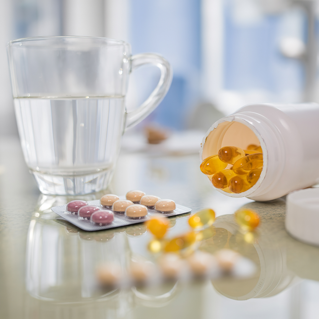 Cold-pressed capsules and tablets with water glass on table