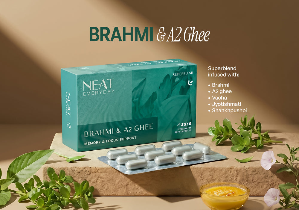 NEAT Everyday BrahmI & A2 Ghee memory and focus support supplement, featuring a teal-green product box, a silver blister pack of white tablets, and a small bowl of yellow ghee on a beige stone pedestal with botanical props.